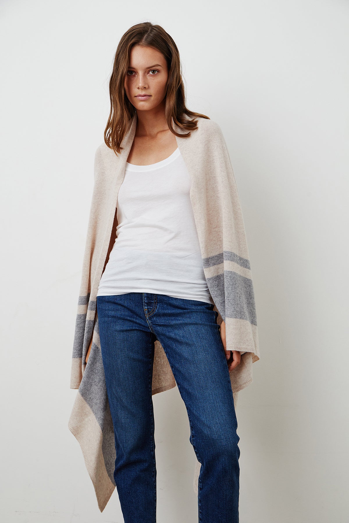   The model is wearing cozy LIV CASHMERE THROW BLANKET jeans and a beige striped cardigan from Jenny Graham Home. 