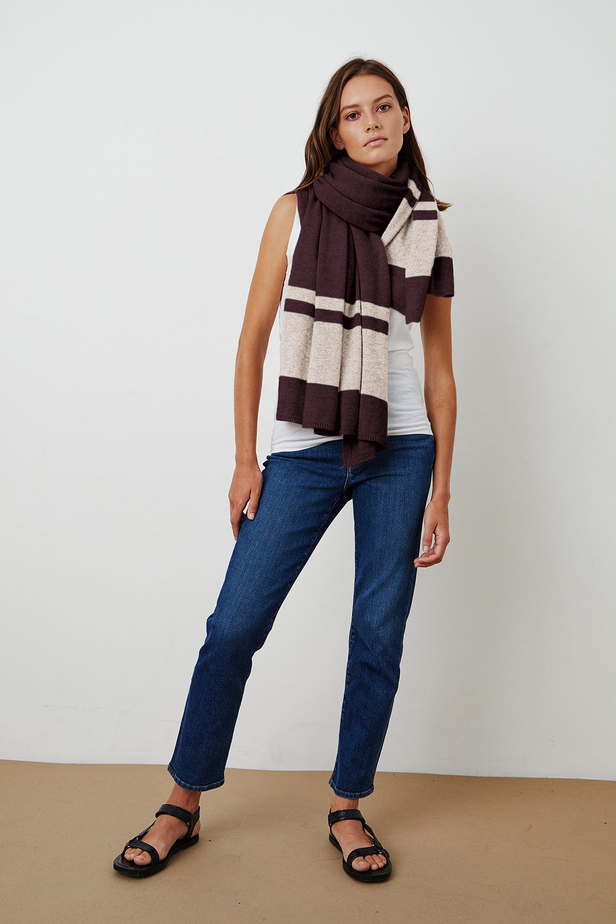   A woman wearing cozy jeans and a luxurious Jenny Graham Home LIV Cashmere Throw Blanket. 