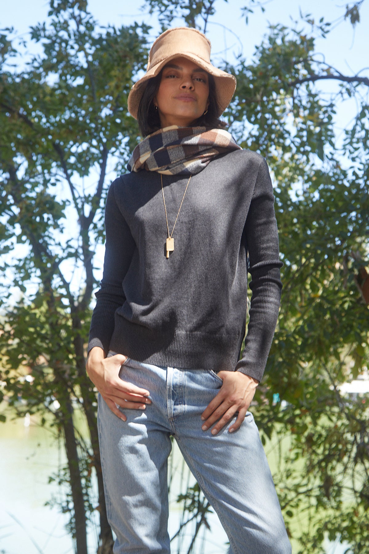 A woman in jeans and a Velvet by Graham & Spencer RENNY TURTLENECK SWEATER standing next to a lake.-25421360398529