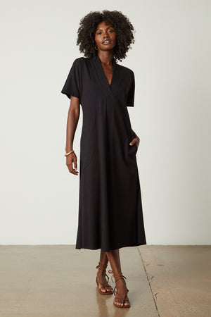 a woman wearing a black Velvet by Graham & Spencer NORA STRUCTURED DRESS and sandals.