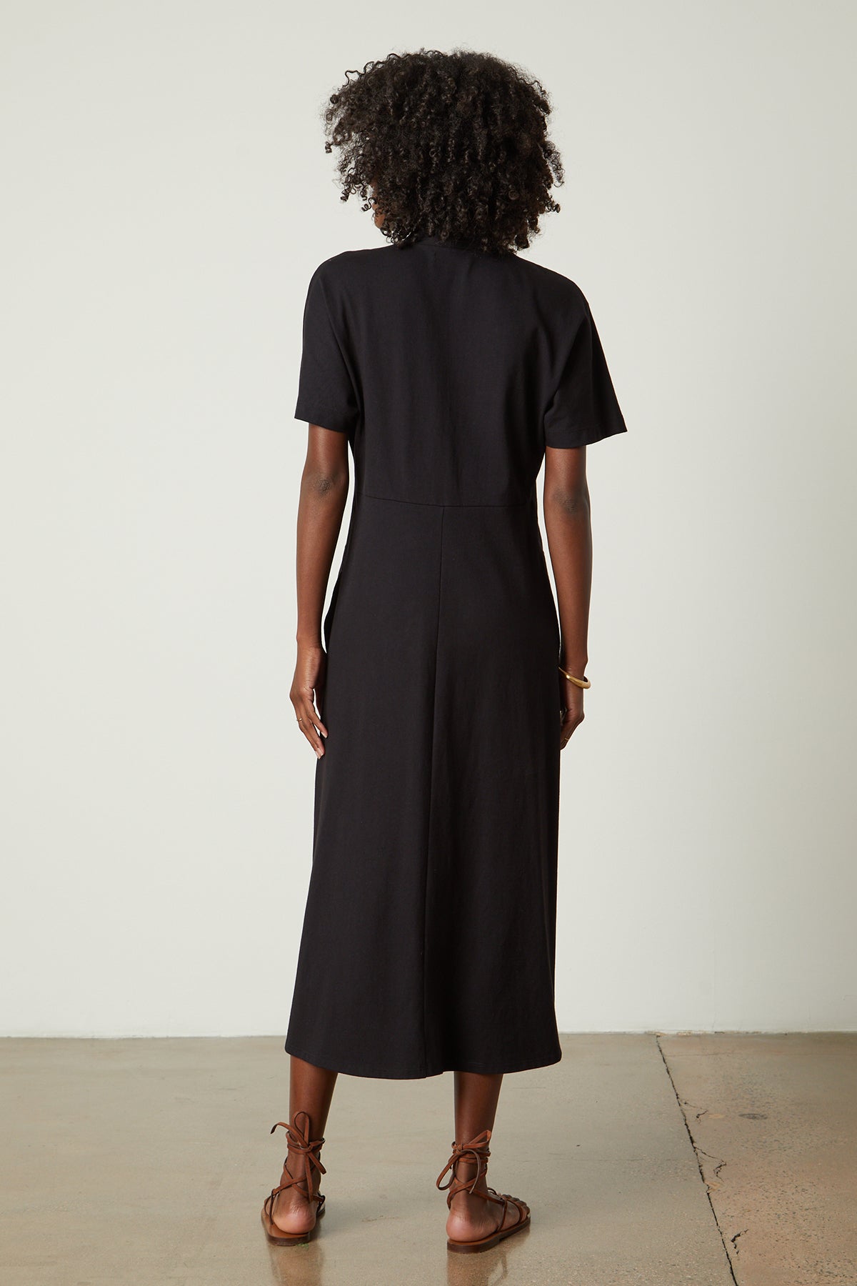 The back view of a woman wearing a black Velvet by Graham & Spencer NORA STRUCTURED DRESS.-26143079563457