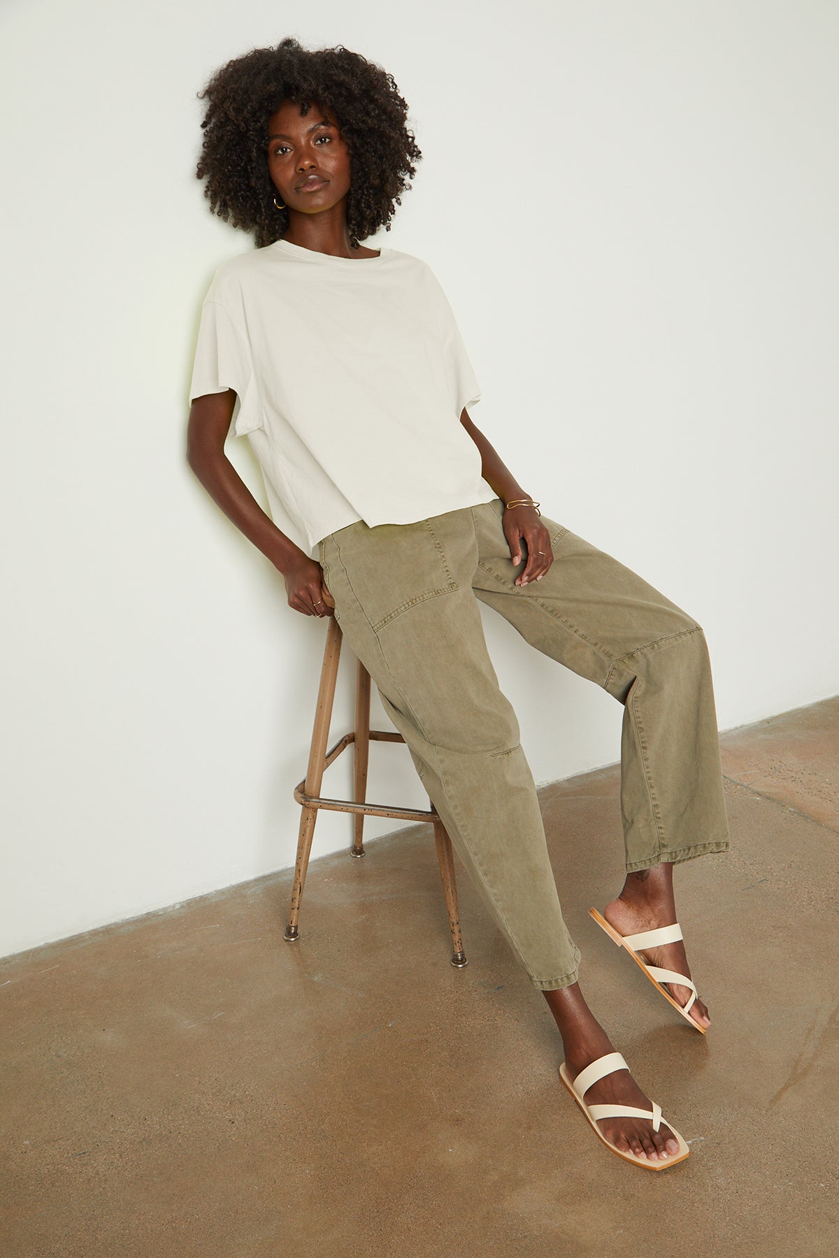 a woman sitting on a stool wearing a Velvet by Graham & Spencer Rachelle Oversized Crew Neck Tee and khaki pants.-26182403850433