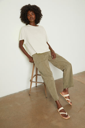 a woman sitting on a stool wearing a Velvet by Graham & Spencer Rachelle Oversized Crew Neck Tee and khaki pants.