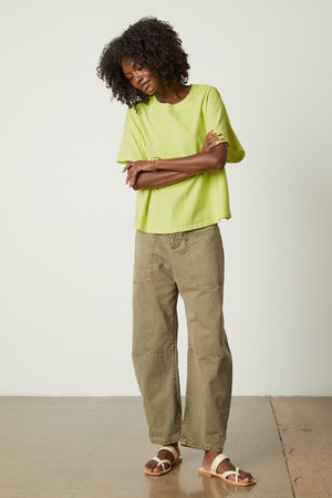a woman wearing a Velvet by Graham & Spencer RACHELLE OVERSIZED CREW NECK TEE top and green pants.