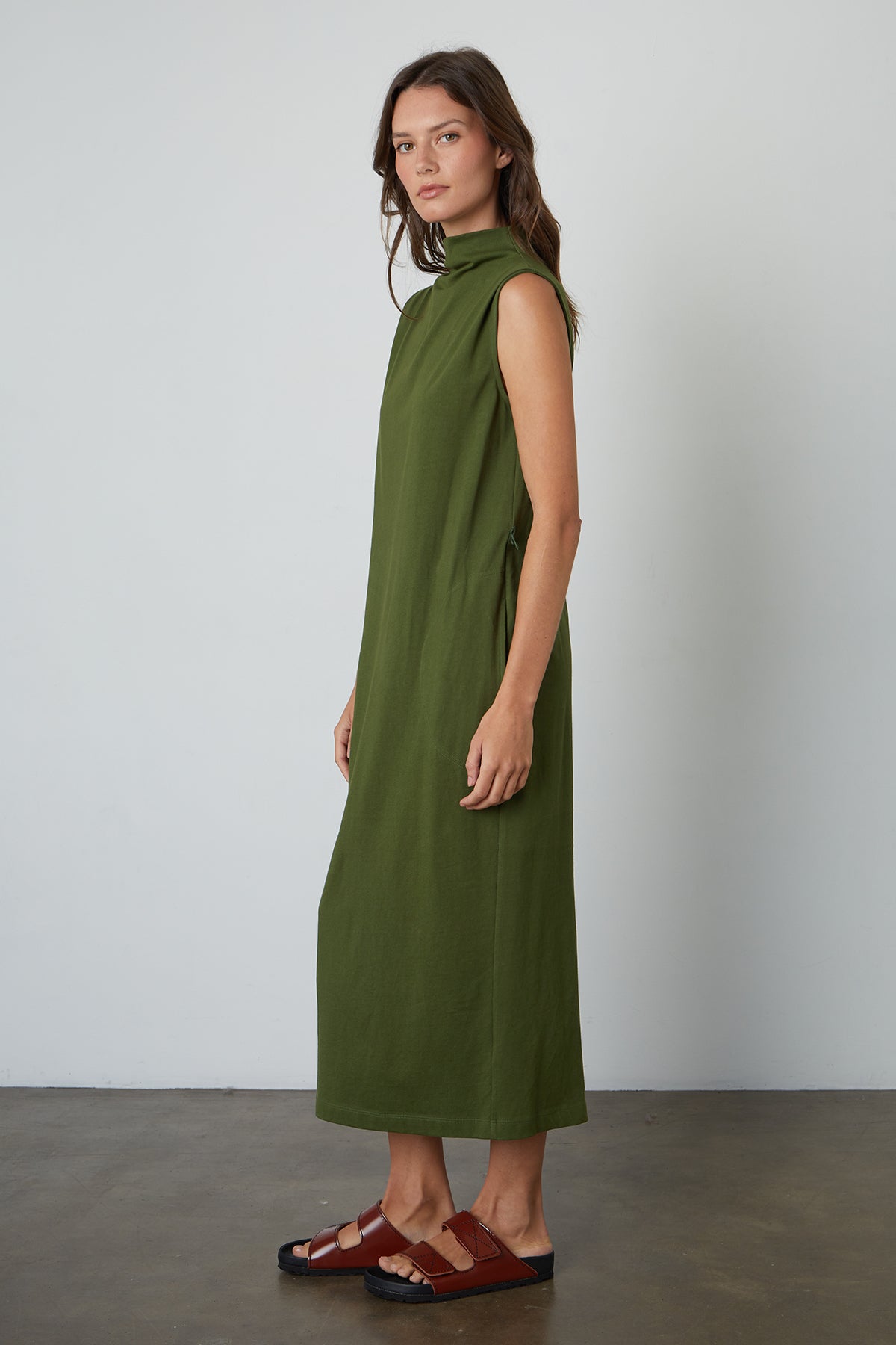   A woman wearing a green Velvet by Graham & Spencer HYDIE MOCK NECK DRESS and sandals. 