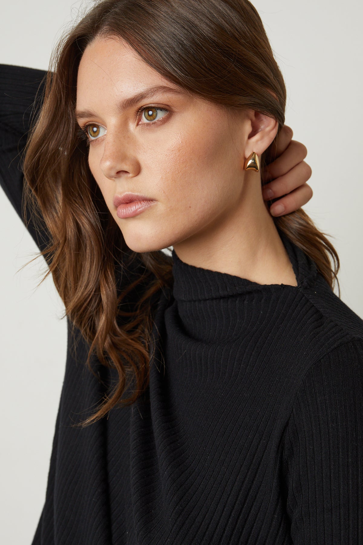   The model is wearing a Velvet by Graham & Spencer DEANNA MOCK NECK TOP and earrings. 