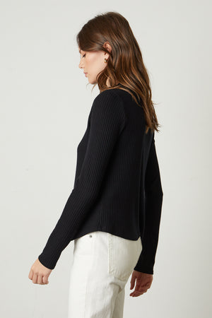 The back view of a woman wearing a black ribbed Velvet by Graham & Spencer Deanna Mock Neck Top and white jeans.
