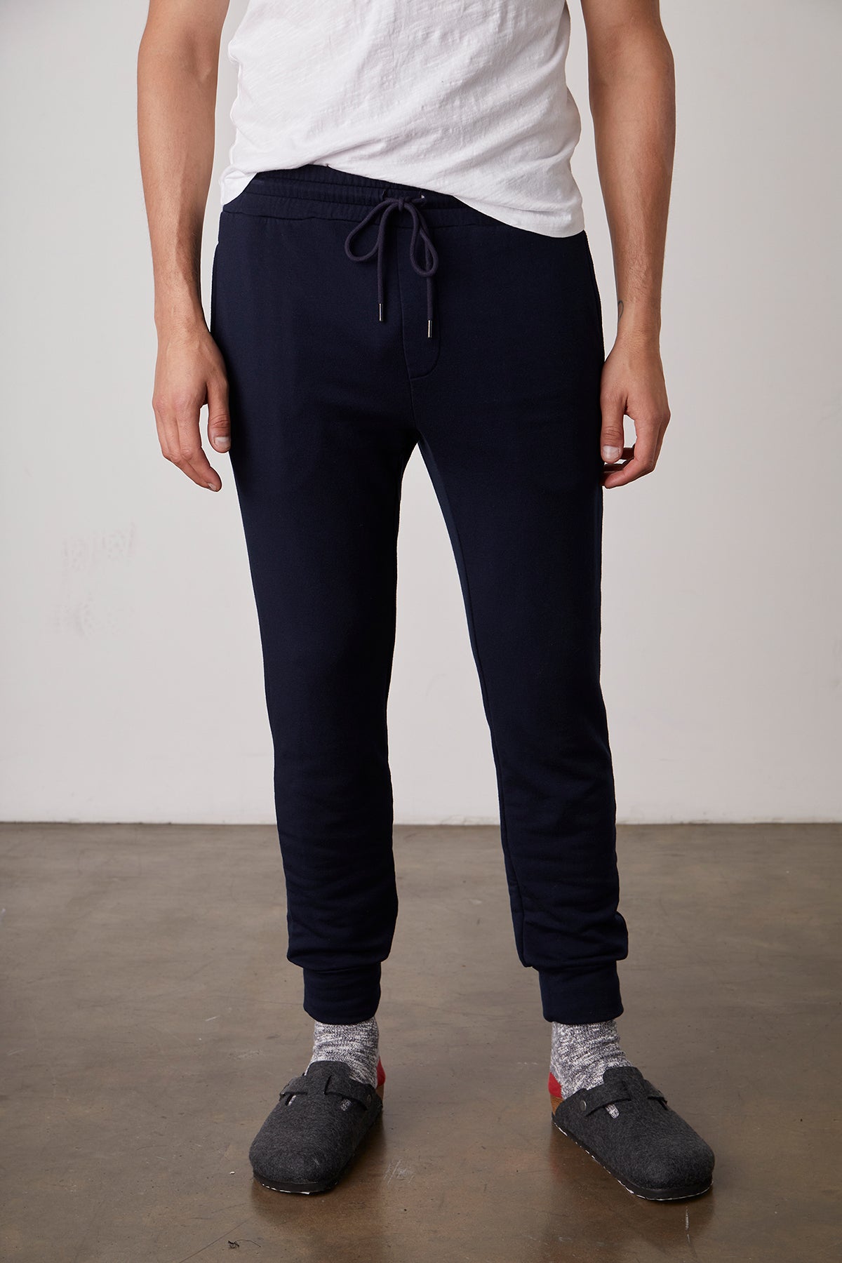   A man wearing CROSBY LUXE FLEECE JOGGER sweatpants by Velvet by Graham & Spencer and white sneakers. 
