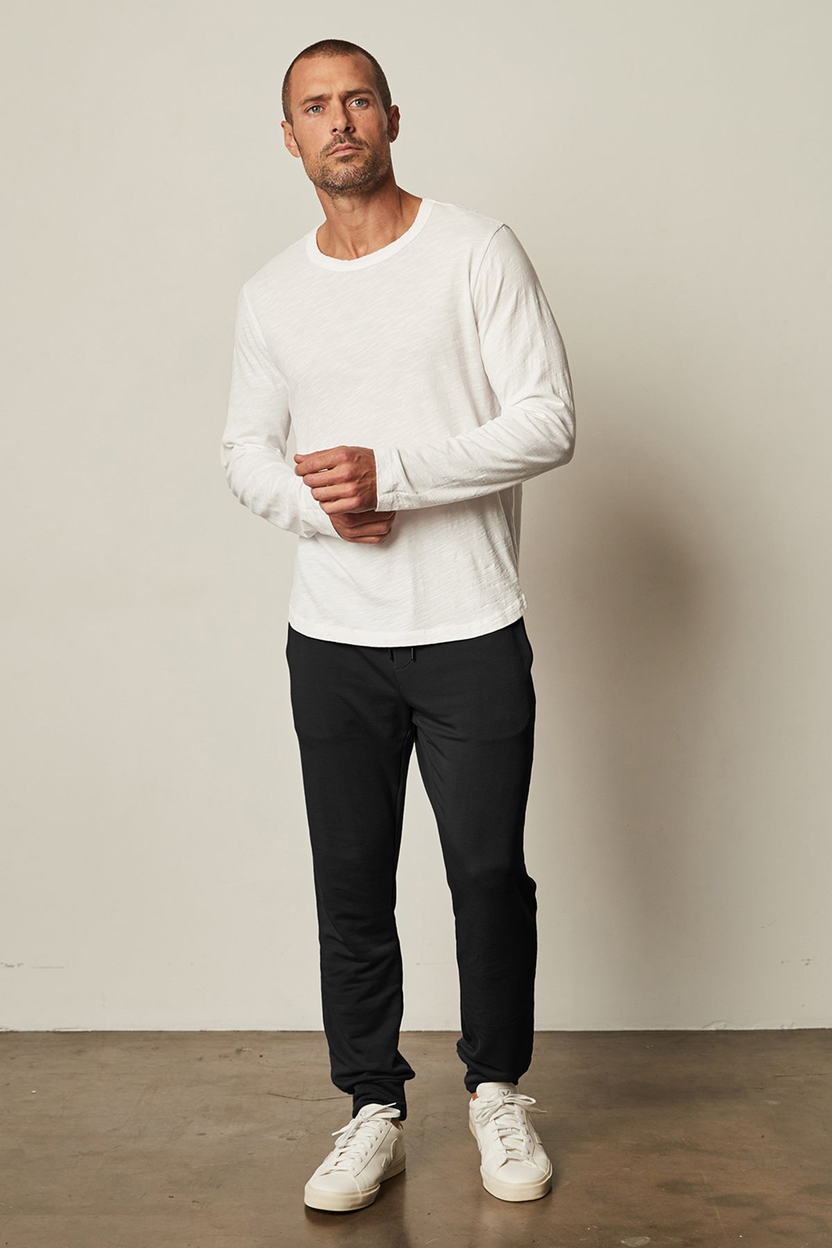 A man wearing a white t - shirt and black Velvet by Graham & Spencer CROSBY LUXE FLEECE JOGGER.-25682959106241
