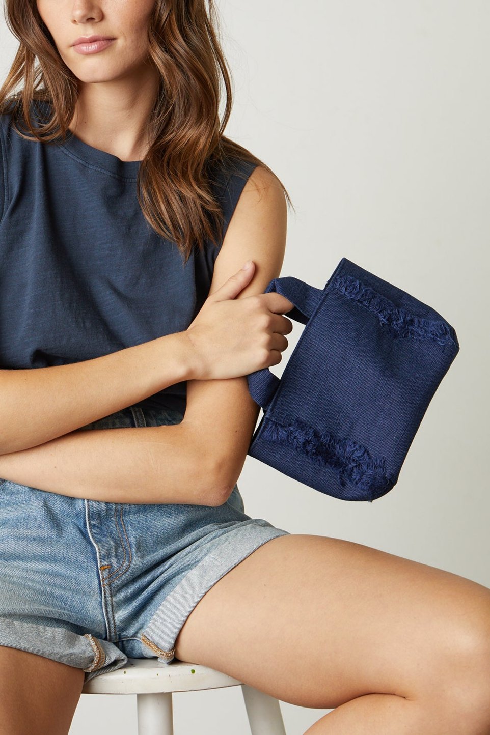   Mini Launch canvas tote in natural with model wearing navy tank and denim shorts 