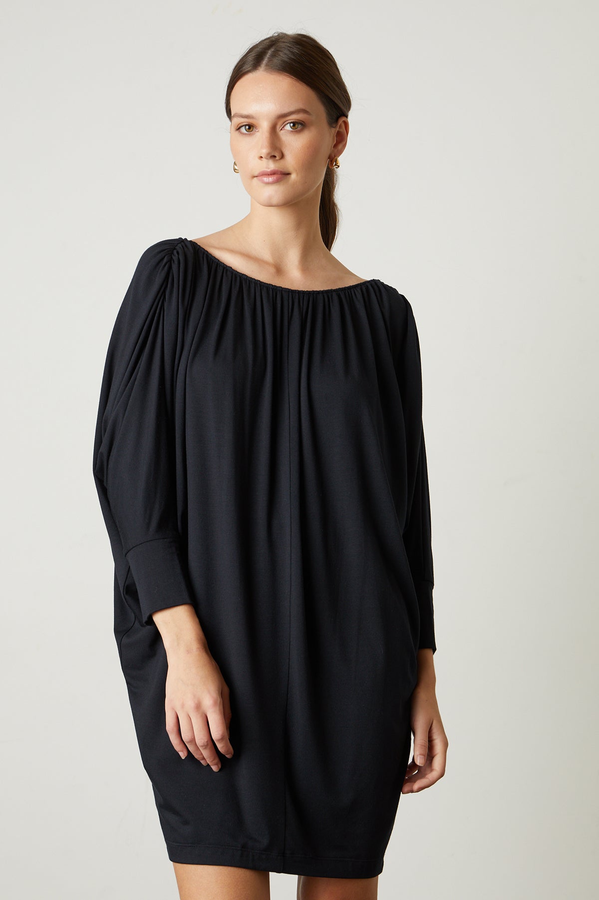   A woman wearing a HOLLIE DRAPE BOAT NECK DRESS dress by Velvet by Graham & Spencer with long sleeves. 
