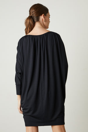The back view of a woman wearing the Velvet by Graham & Spencer HOLLIE DRAPE BOAT NECK DRESS.