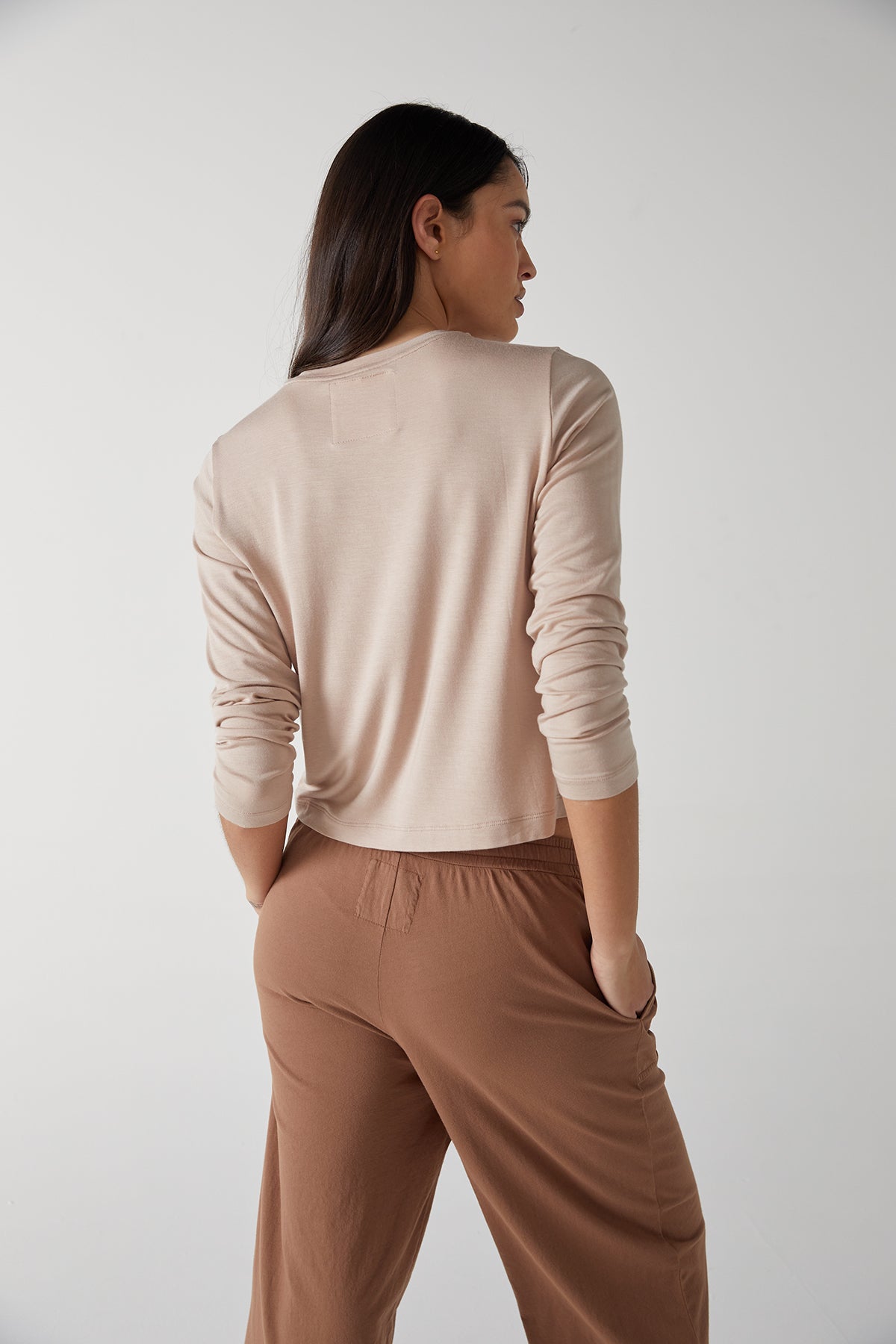   The back view of a woman wearing Velvet by Jenny Graham tan wide leg pants. 