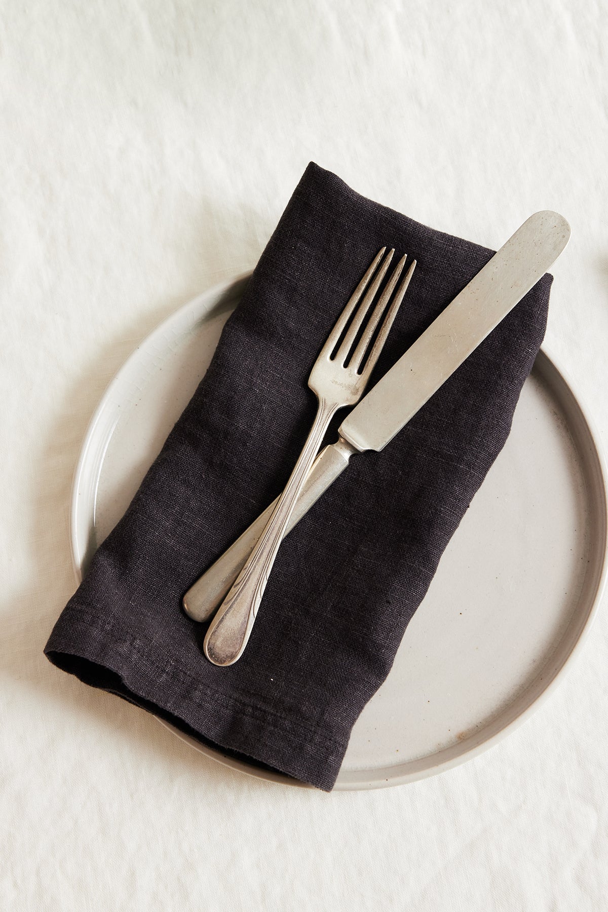   Jenny Graham Home linen napkin with fork and knife on a white plate, an everyday kitchen essential with a luxe finish. 