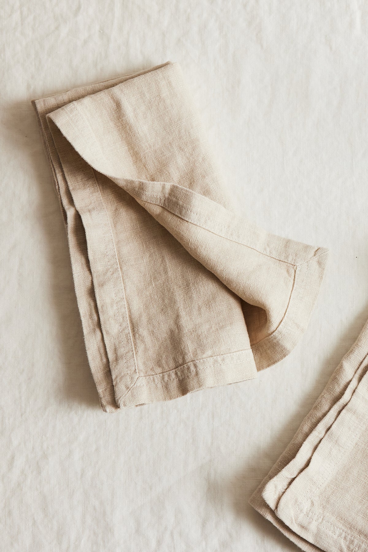   A set of Jenny Graham Home luxe finish linen napkins, an everyday kitchen essential, on a white surface. 