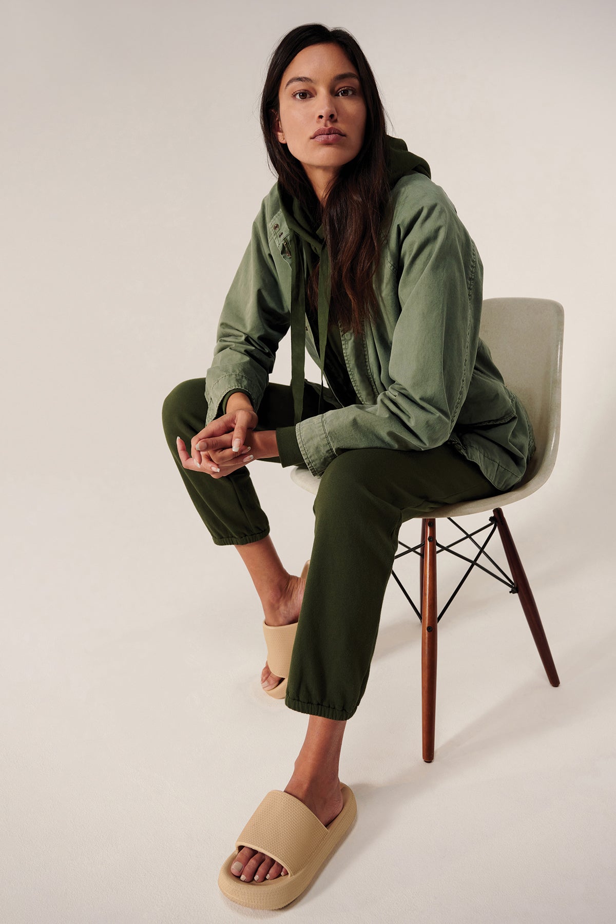   A model is sitting on a chair in a Velvet by Jenny Graham Melrose Jacket and sandals. 