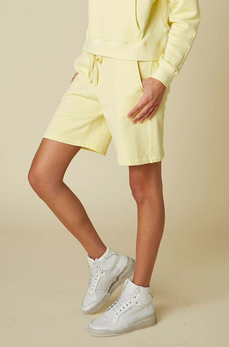 The model is wearing a yellow LAGUNA SWEATSHORT hoodie and shorts by Velvet by Jenny Graham.-24063592136897