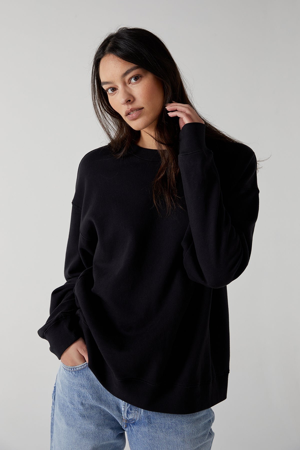   The model is wearing a black ABBOT SWEATSHIRT by Velvet by Jenny Graham and jeans. 