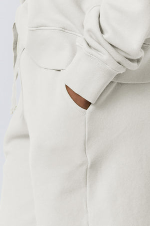 a woman wearing Velvet by Jenny Graham LAGUNA SWEATSHORT sweatpants and a white hoodie.