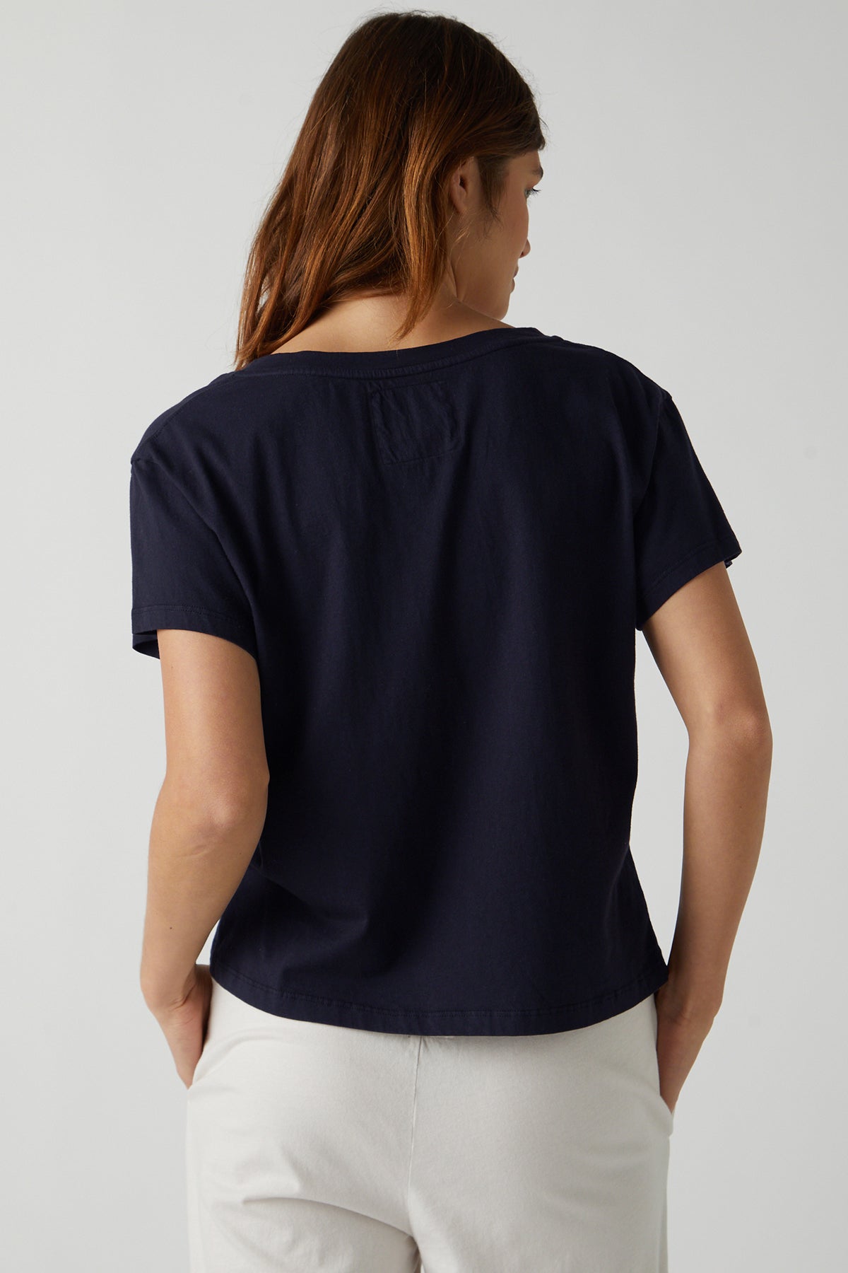 The back of a woman wearing a Velvet by Jenny Graham VENICE TEE and white pants.-25484413960385