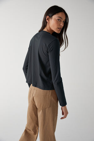 The back view of a woman wearing tan trousers and a black long sleeved VICENTE TEE by Velvet by Jenny Graham.