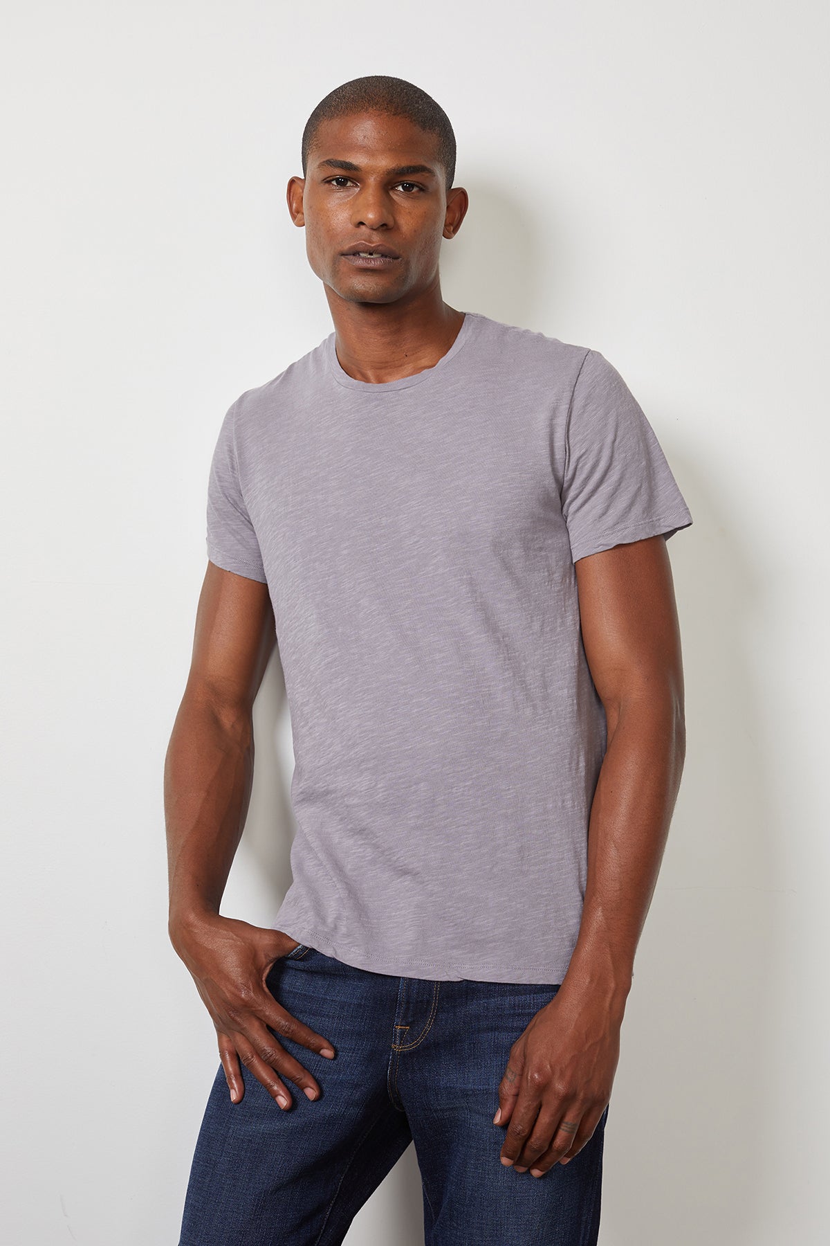 A man wearing a Velvet by Graham & Spencer Dion Crew Neck Tee made of cotton knit fabric and jeans.-22095008137409