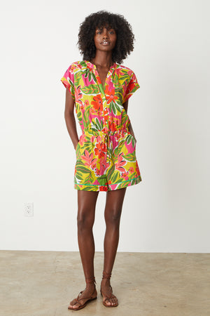 Pam Romper in bold floral aloha print with reds, hot pinks and greens full length front models hands in both pockets