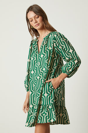 The model is wearing a Velvet by Graham & Spencer FELICITY PRINTED BOHO DRESS with a ruffled hemline.