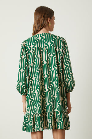 The back view of a woman wearing a green Velvet by Graham & Spencer FELICITY PRINTED BOHO DRESS.