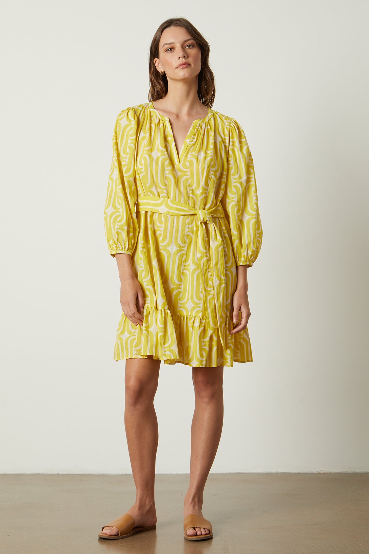 A woman wearing a yellow FELICITY PRINTED BOHO DRESS by Velvet by Graham & Spencer with mod-inspired print and sandals.-26235560984769