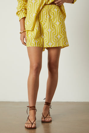 a woman wearing a yellow shirt and Velvet by Graham & Spencer LYNNE PRINTED SHORTS.