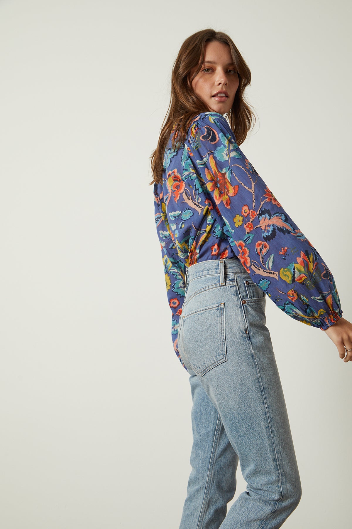   Camryn Top in colorful spring floral print tucked into blue denim side & back accentuating sleeve  