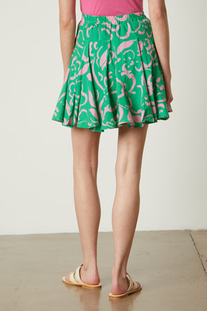 The back view of a woman wearing an ELSA PRINTED SKIRT by Velvet by Graham & Spencer.