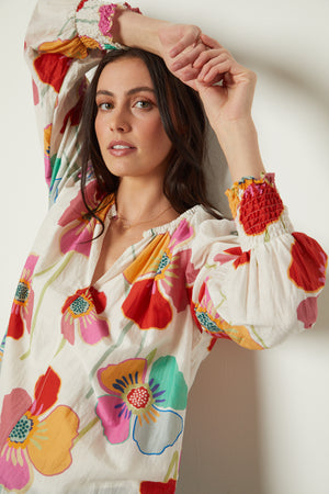 Avery Top in bold floral print with cream background close up model standing against wall with arms above her head