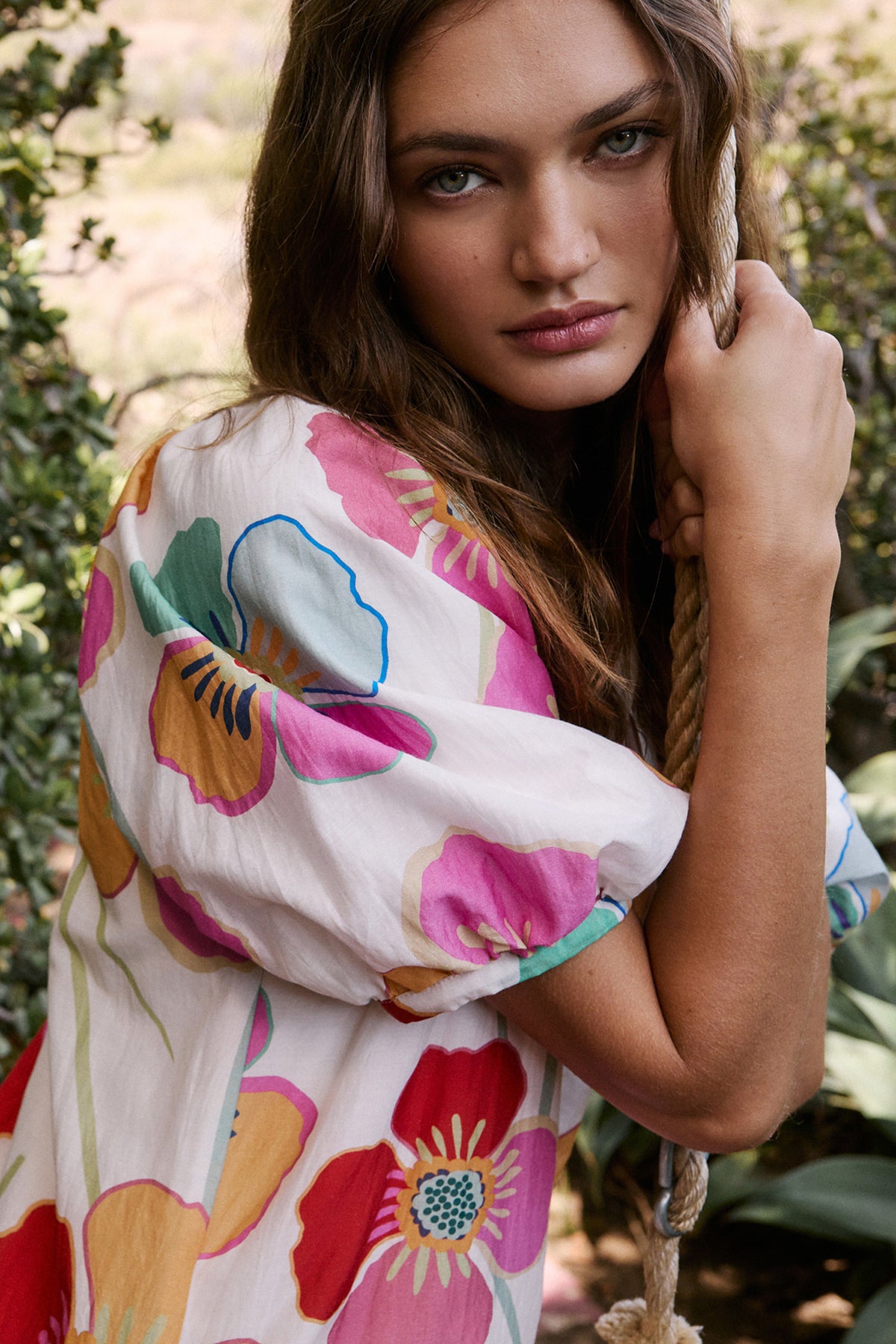   Rachel Dress in bold floral print on cream background sleeve detail lookbook image modeling sitting on swing 