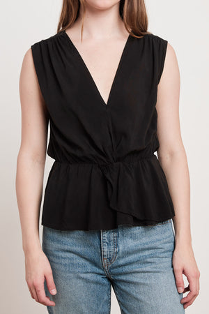 A woman in a black top and jeans with an ADALI WRAP BLOUSE by Velvet by Graham & Spencer.