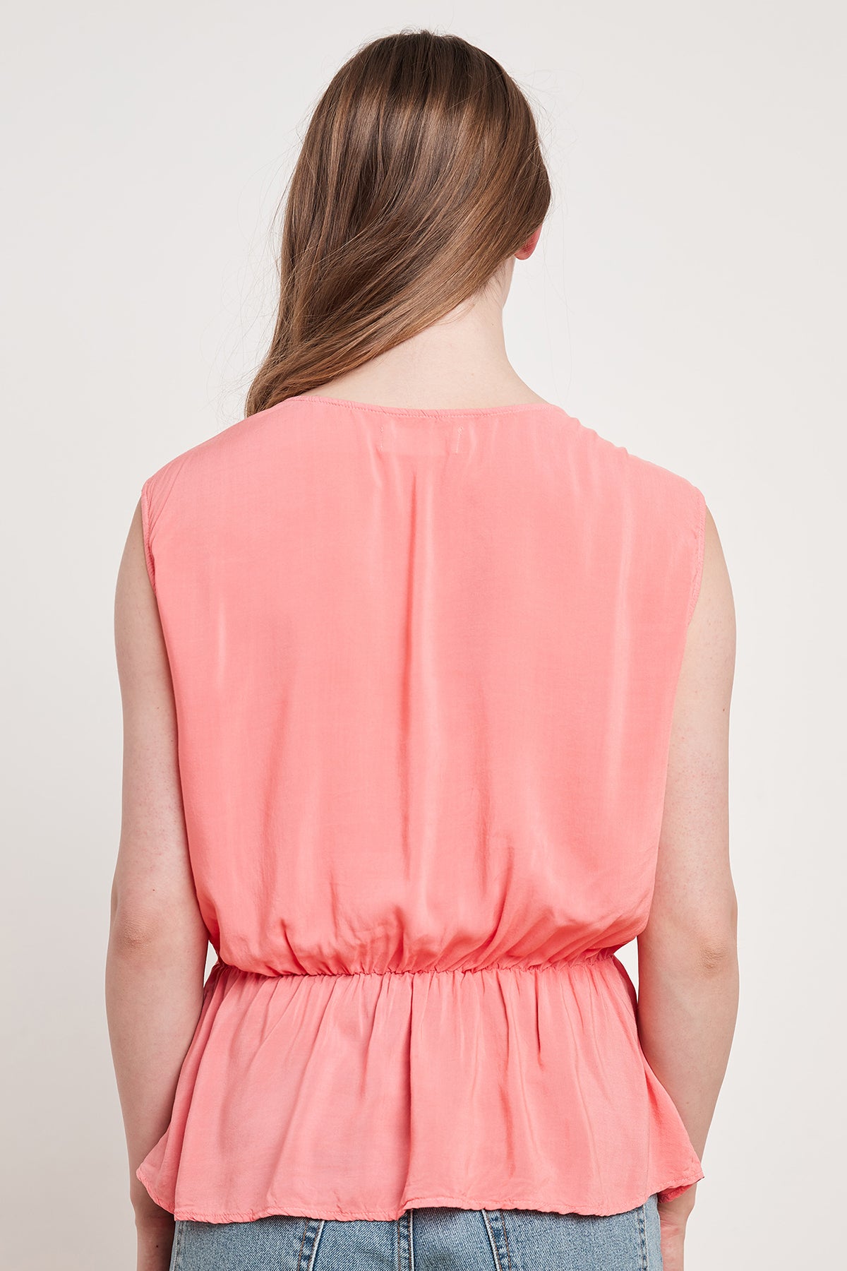 The woman is wearing a pink ADALI WRAP BLOUSE from Velvet by Graham & Spencer, showcasing a cinched waist.-14925316358337