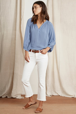 The model is wearing a blue blouse and white pants. [Product Name: MOCKINGBIRD SANDAL BY BEEK, Brand Name: Beek]