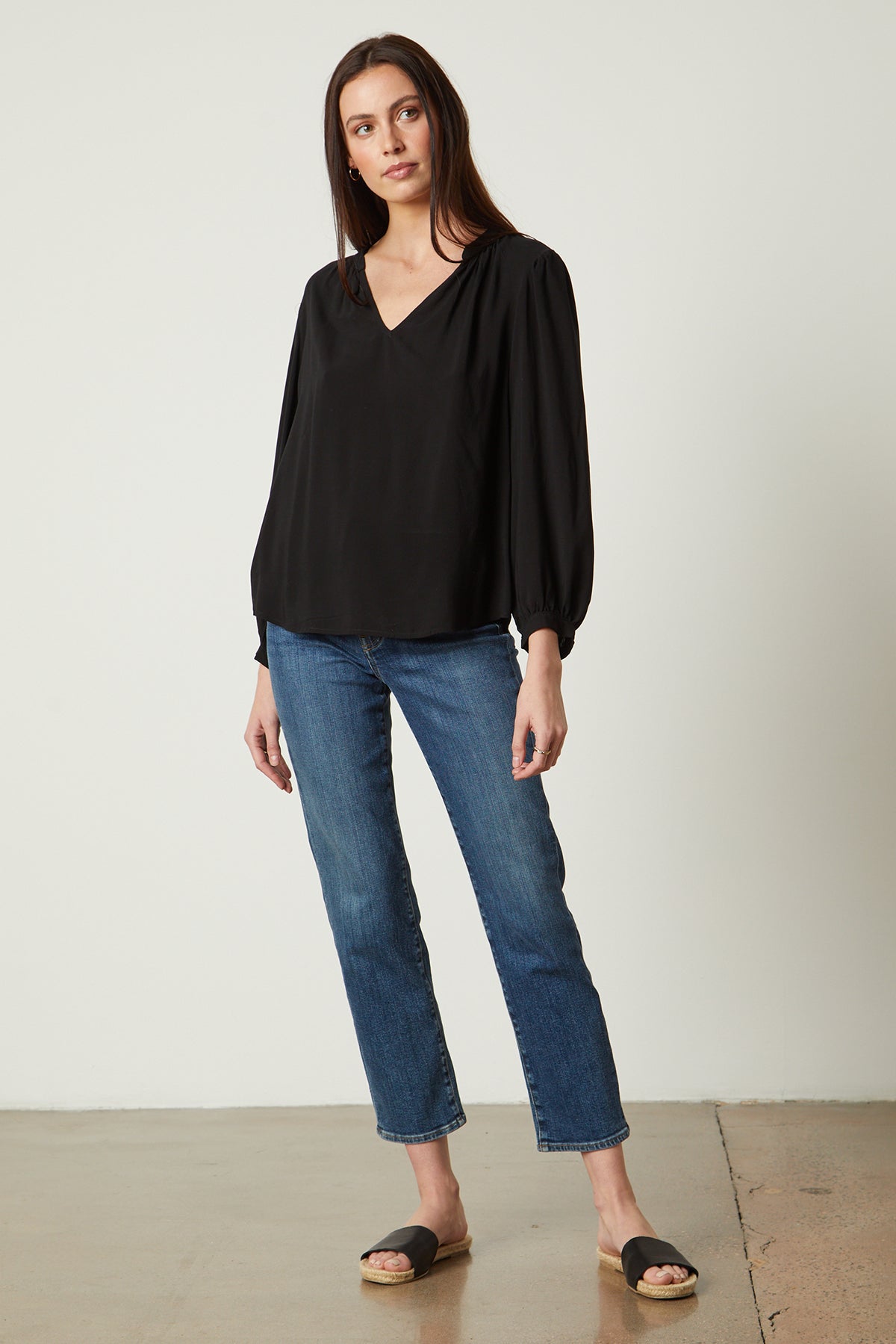   a woman wearing jeans and the Emily V-Neck Blouse by Velvet by Graham & Spencer. 