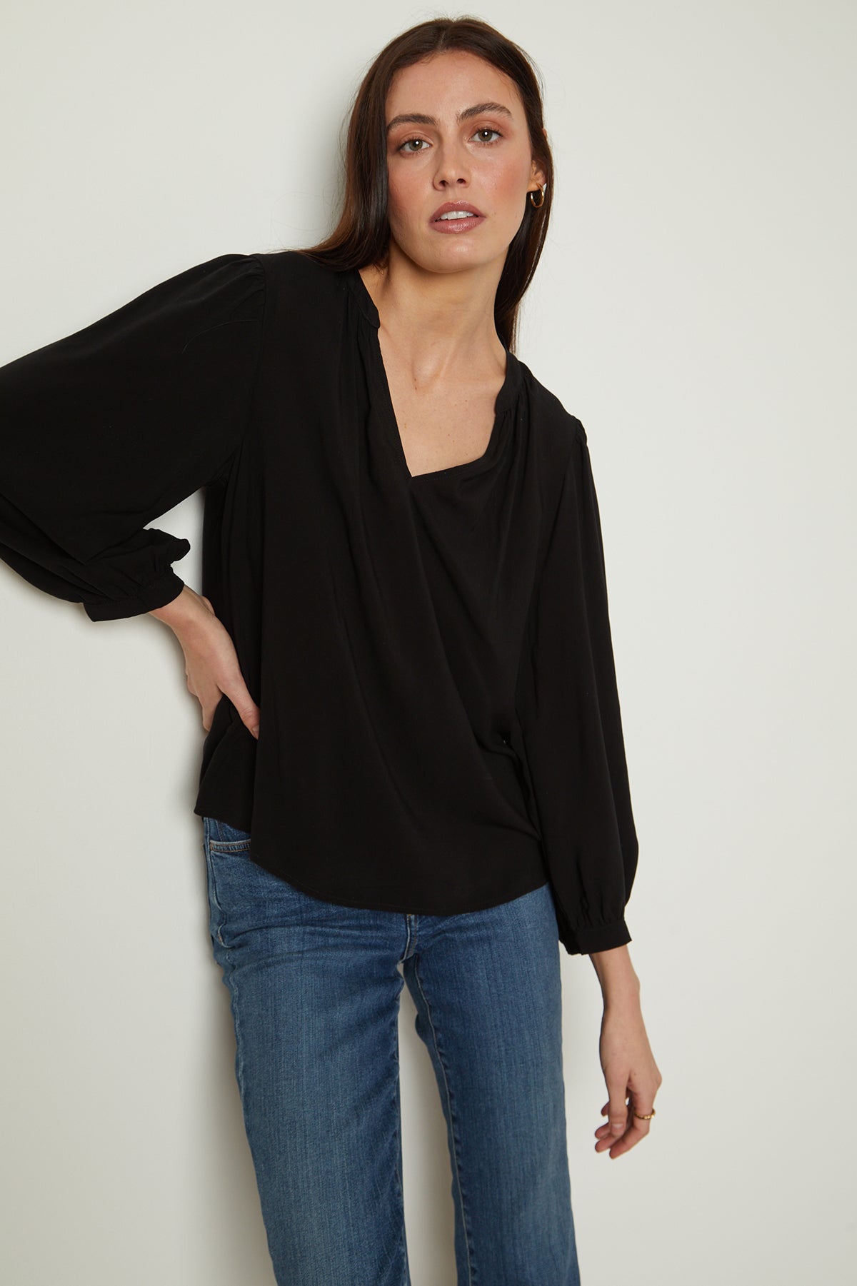 The model is wearing black jeans and the EMILY V-NECK BLOUSE by Velvet by Graham & Spencer.-25954485829825