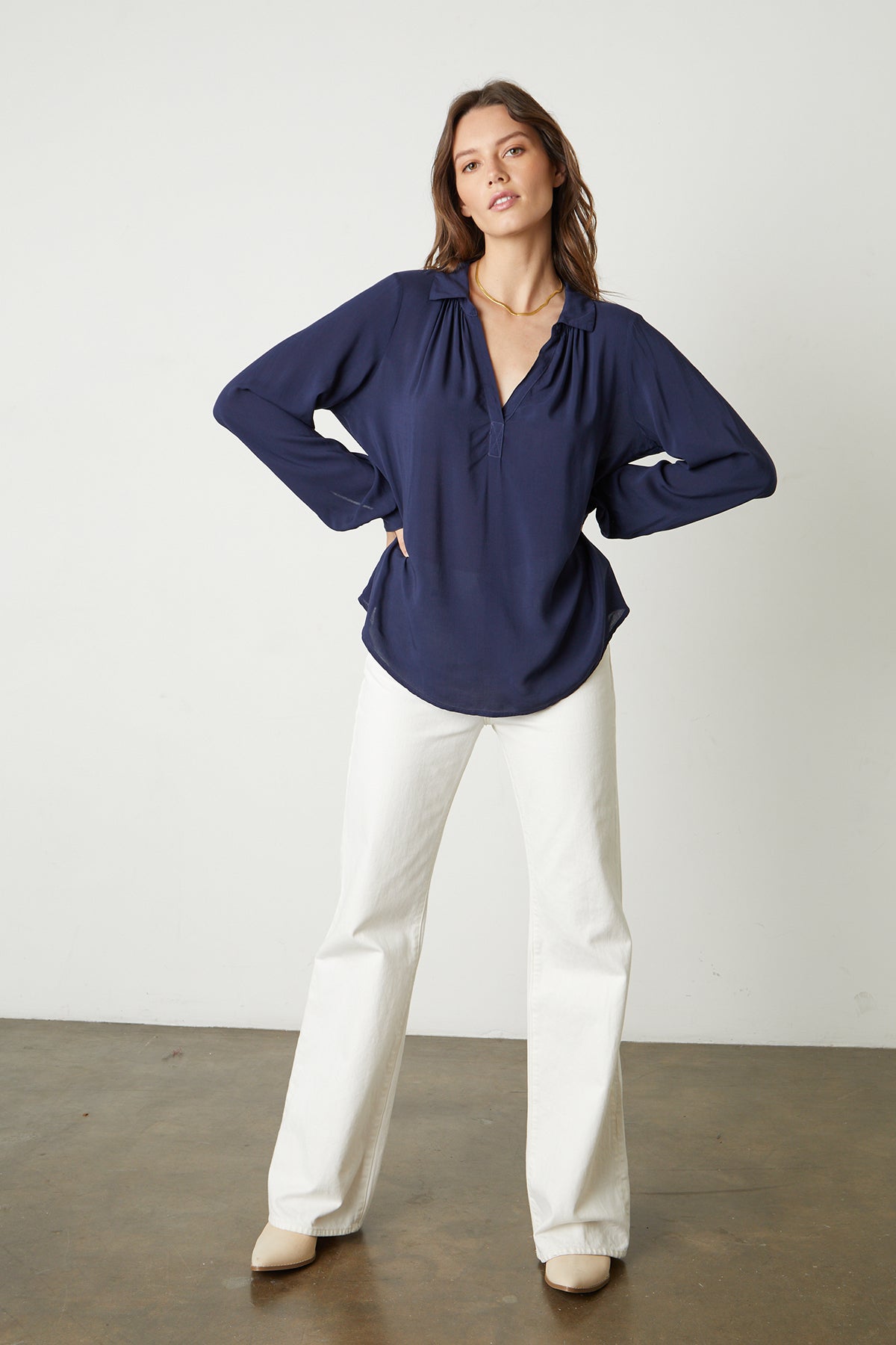   the model is wearing a Velvet by Graham & Spencer JOSEY V-NECK COLLAR TOP and white wide leg pants. 