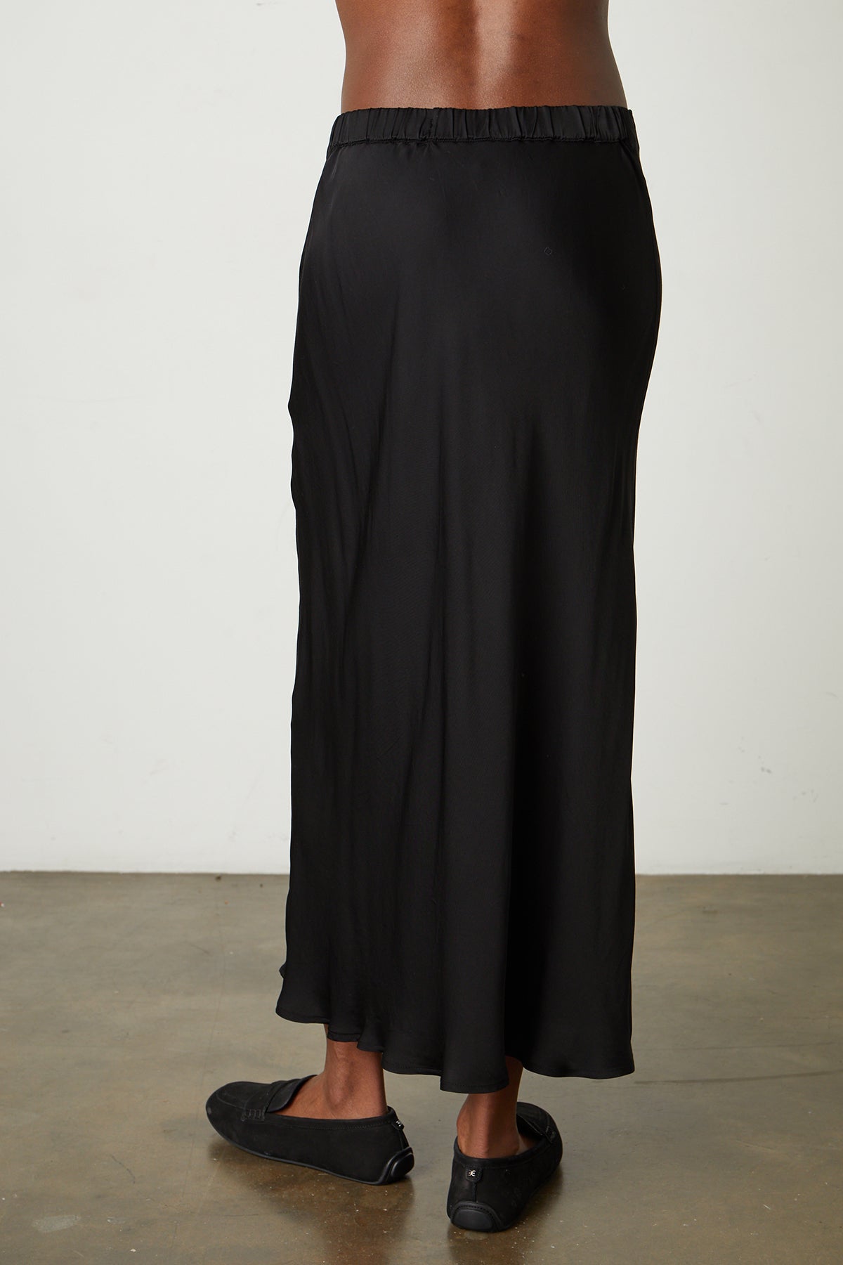   The back of a woman wearing the Velvet by Graham & Spencer AUBREE SATIN MIDI SKIRT. 