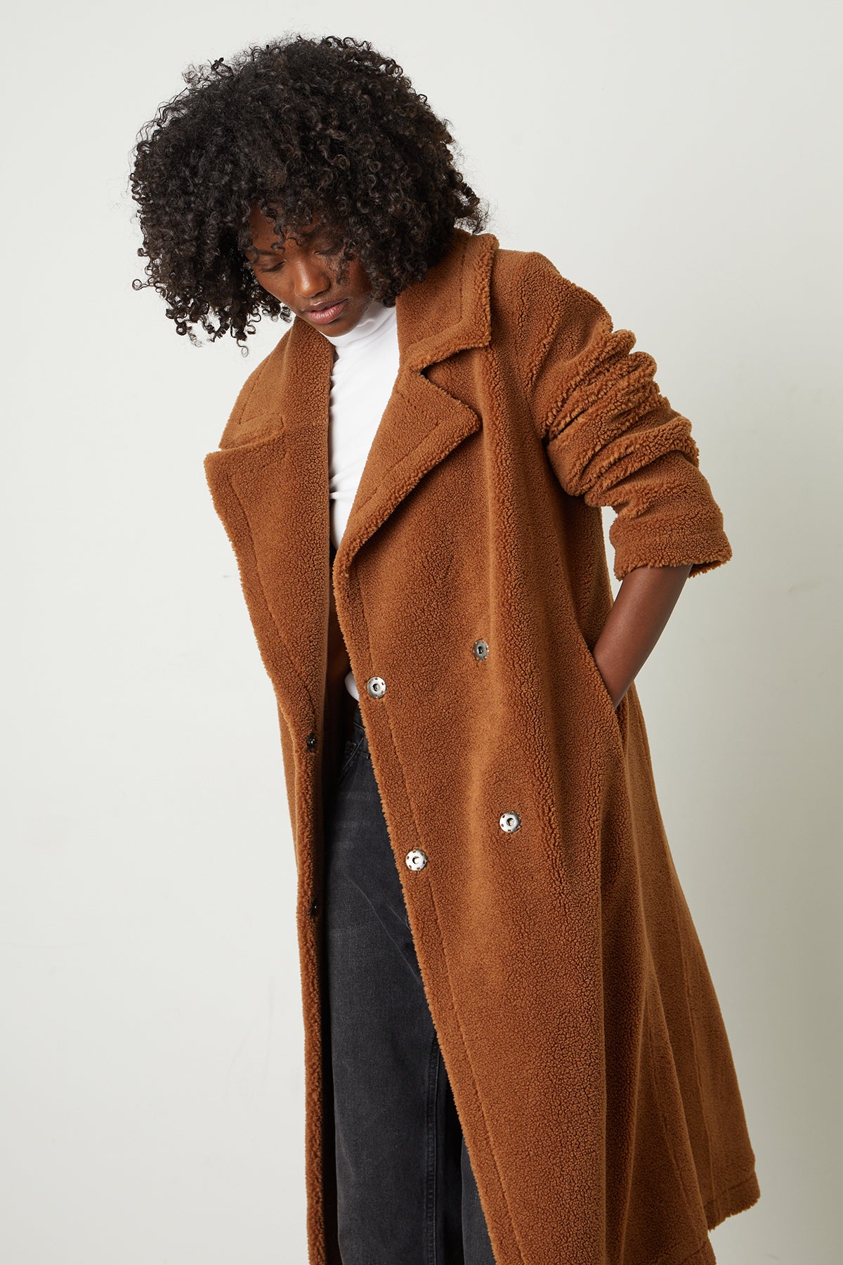   A woman wearing a REINA FAUX SHEARLING COAT by Velvet by Graham & Spencer with popper button closures. 