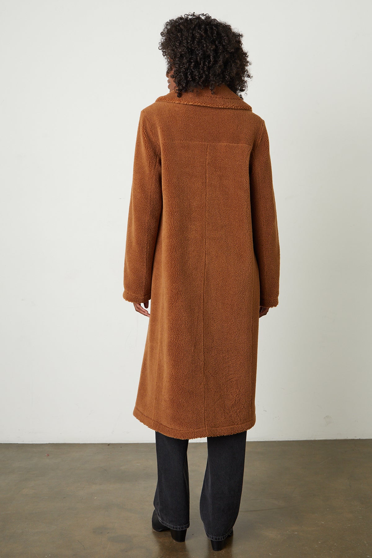   The back view of a woman wearing a Velvet by Graham & Spencer REINA FAUX SHEARLING COAT. 