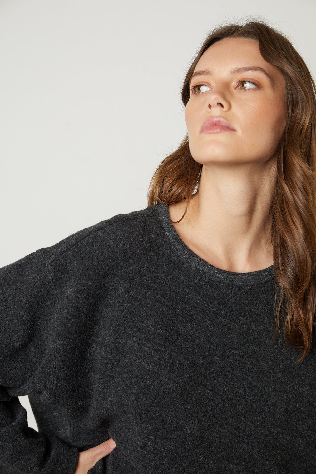  The model is wearing a black Arissa Cropped Sweatshirt by Velvet by Graham & Spencer with long sleeves. 
