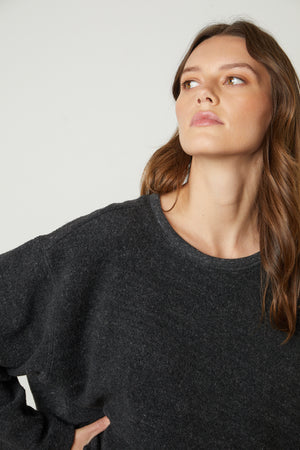 The model is wearing a black Arissa Cropped Sweatshirt by Velvet by Graham & Spencer with long sleeves.