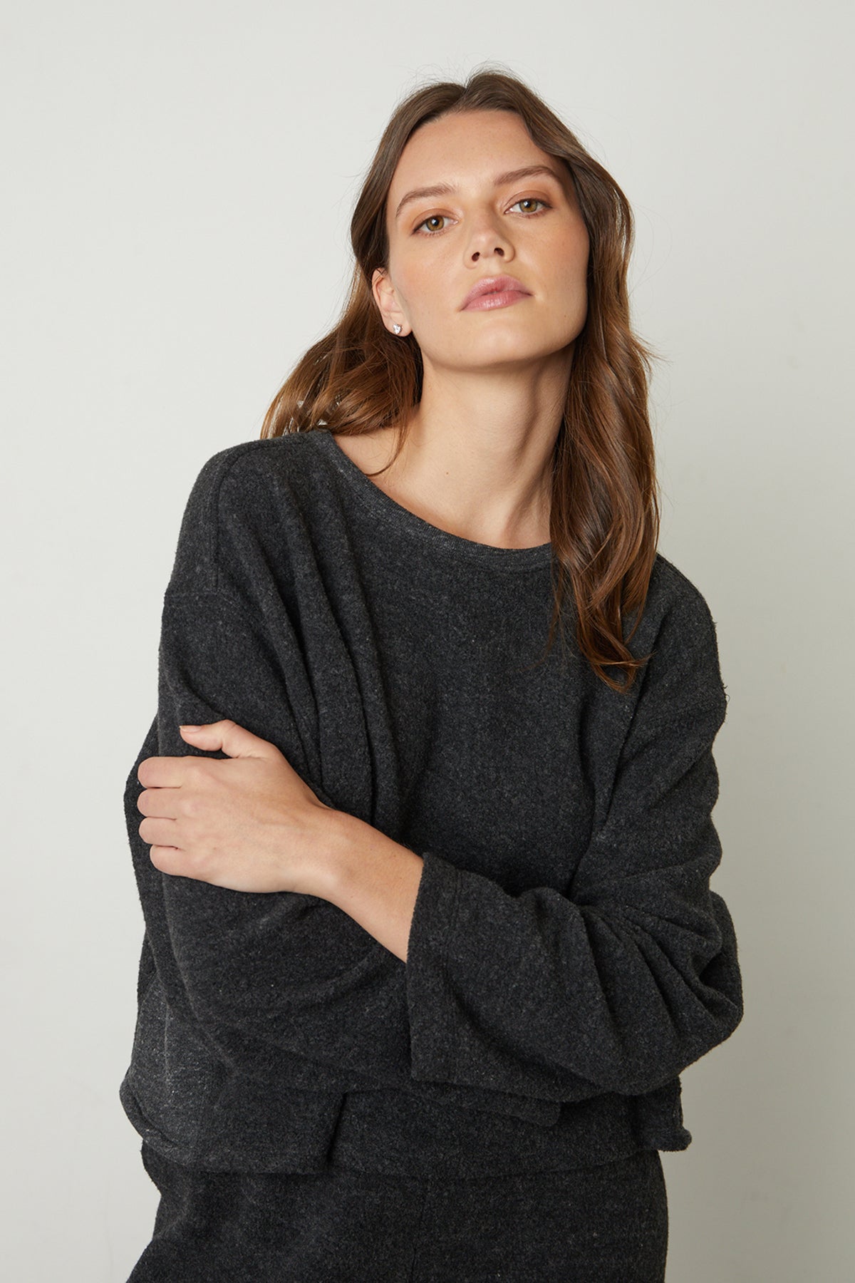   The model is wearing a black Arissa Cropped Sweatshirt and jeans by Velvet by Graham & Spencer. 