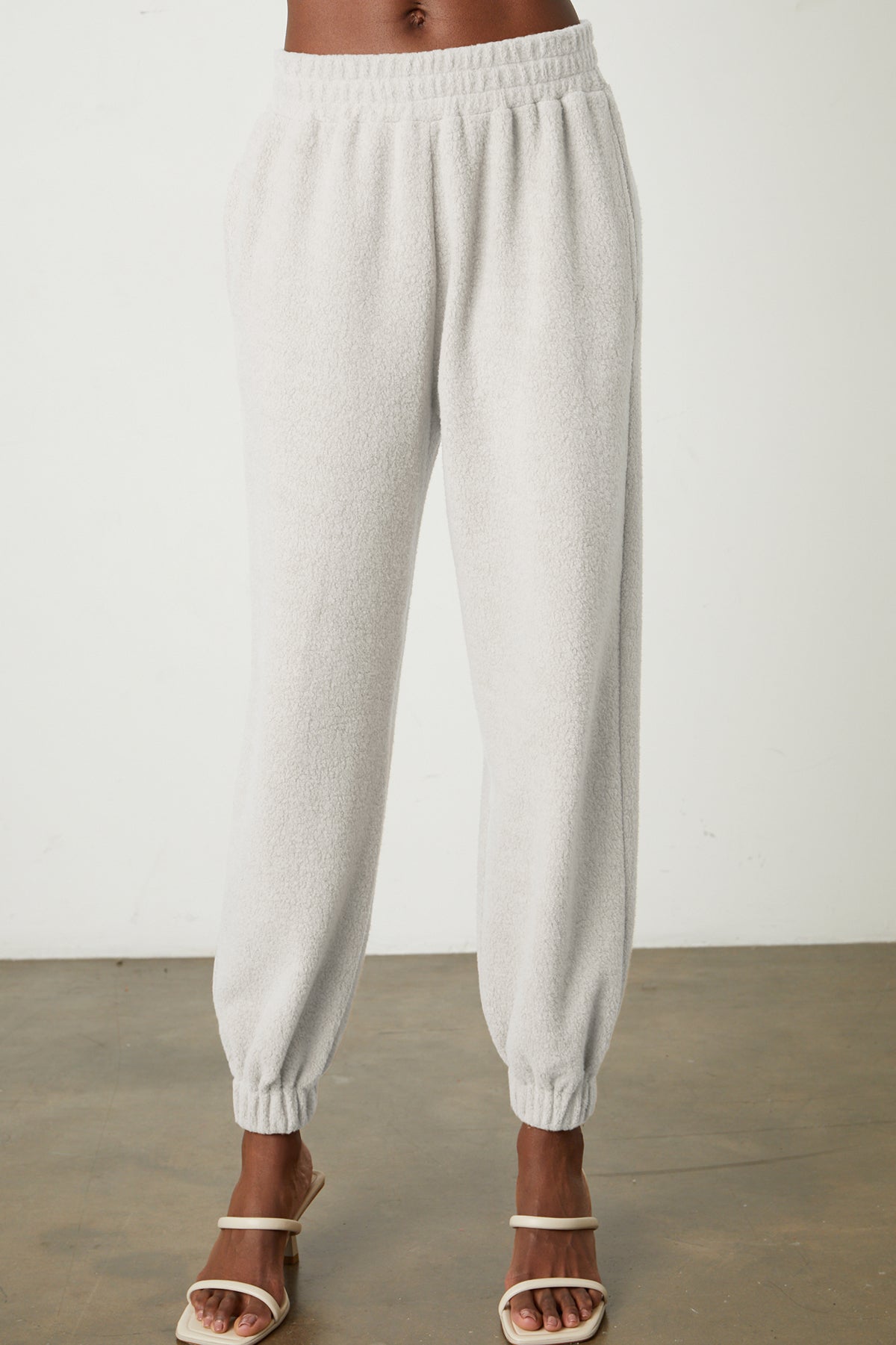 a woman wearing Velvet by Graham & Spencer BROOKIE FLEECE JOGGER sweatpants and sandals.-26067963642049