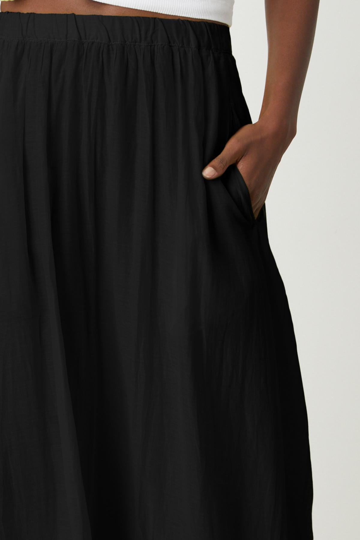 A woman wearing a black Mariela Maxi Skirt with pockets by Velvet by Graham & Spencer pocket detail-26262257926337