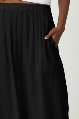 A woman wearing a black Mariela Maxi Skirt with pockets by Velvet by Graham & Spencer pocket detail